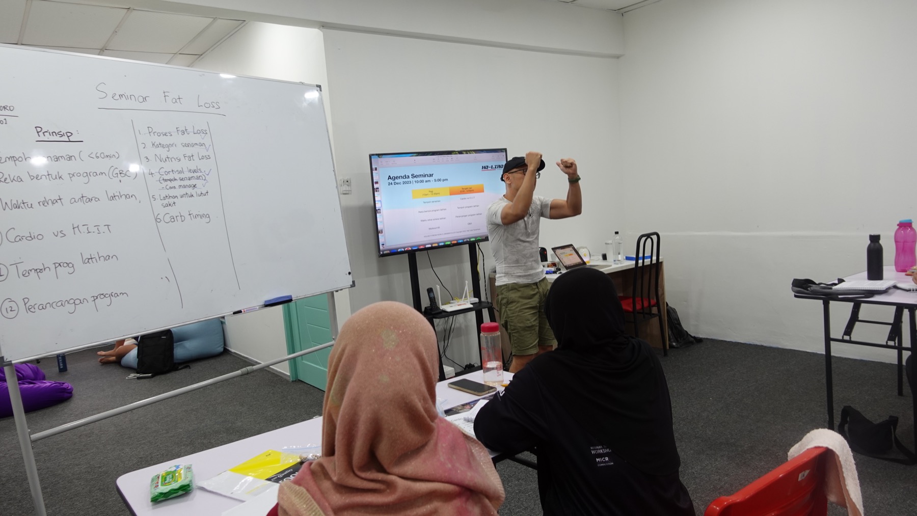 Coach Ho presenting at a fat-loss seminar with attendees and a whiteboard