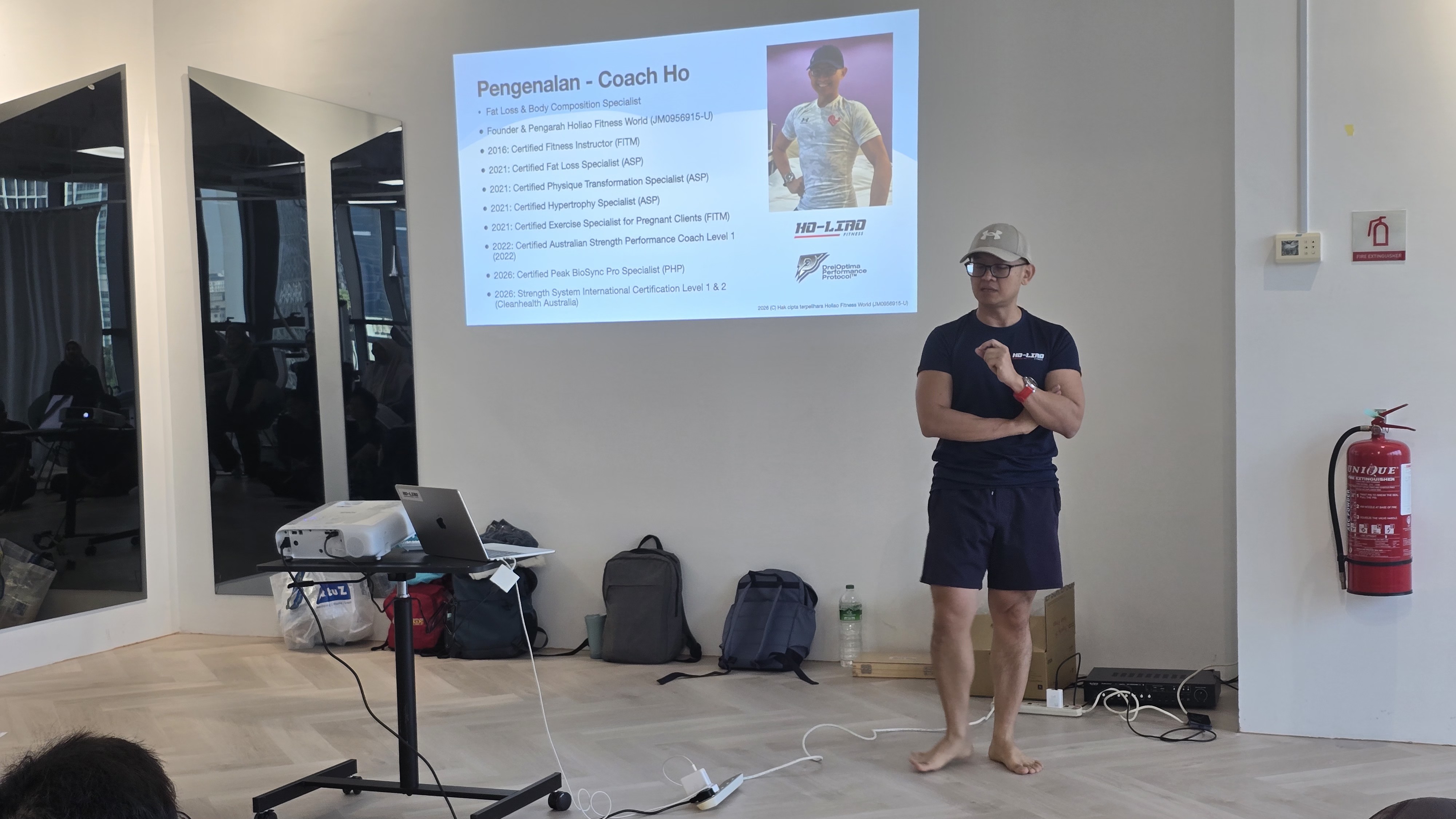 Coach Ho presenting a practical strength-training session beside a projected slide